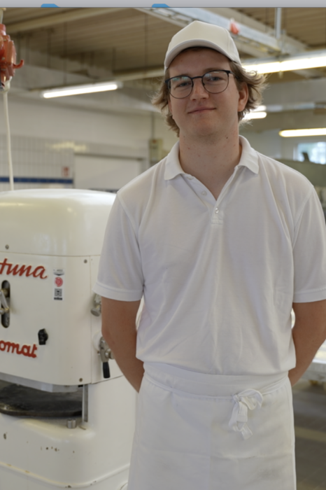 Das Bild zeigt einen jungen Mann mit Brille, stehend. Es handelt sich dabei um den Bäcker Meisterschüler Thies